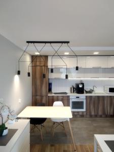 a white kitchen with a table and chairs in it at Family & Business Elegant Apartments Rynek Centrum Downtown - 2 Bedroom, Balcony, Parking in Kielce