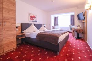 ein Hotelzimmer mit einem großen Bett und einem roten Teppich in der Unterkunft Hotel-Restaurant Weinberg in Artern