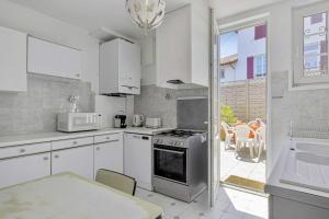 cocina con armarios blancos y fogones en Charming Basque villa with garden - Bayonne - Welkeys, en Bayona