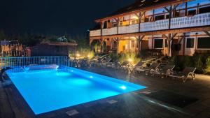 a swimming pool in front of a house at night at Złociste Zacisze in Bobolin