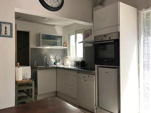 uma cozinha com electrodomésticos de aço inoxidável e um relógio na parede em Villa Henri IV em La Couarde-sur-Mer