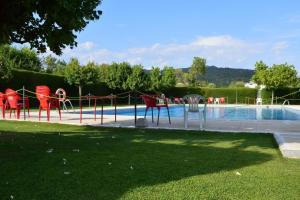 a swimming pool with red chairs next to a swimming pool at Casa Carbonero in Lascuarre