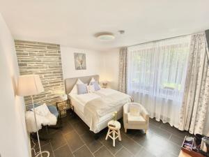 ein Schlafzimmer mit einem Bett, einem Stuhl und einem Fenster in der Unterkunft JUULS - Natur Hotel Garni in Simmerath