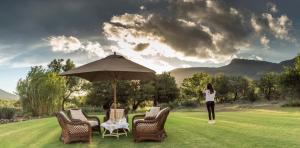 a woman standing next to chairs and an umbrella at Mount Camdeboo Private Game Reserve by NEWMARK in Graaff-Reinet