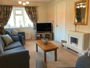 a living room with a couch and a television and a table at Grand eagles Riverside Extra large lodge in Auchterarder