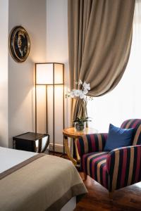 ein Schlafzimmer mit einem Bett, einem Stuhl und einer Lampe in der Unterkunft AQA Palace in Florenz