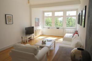 una sala de estar con 2 sofás blancos y una mesa. en VILLA14 en Offenburg