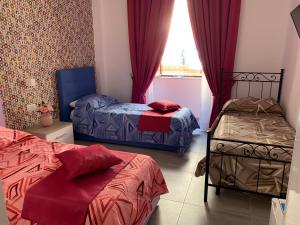 1 dormitorio con 2 camas y una ventana con cortinas rojas en Casa Sammarco, en Nápoles