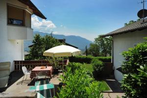 a patio with a table and an umbrella at Haus Rosengarten in Tirolo