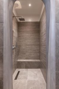 y baño con ducha y pared de piedra. en Secret Garden Apartments en Mykonos ciudad