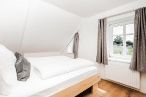 a white bedroom with a bed and a window at Tini´s Feinstes in Mariapfarr