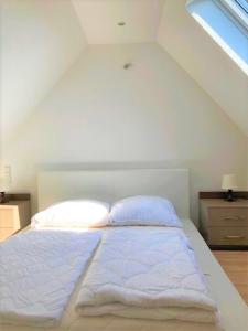 a white bed in a room with a window at Familienfreundliches Ferienhaus AMARA mit Garten und Terrasse - Friedrichshafen am Bodensee in Friedrichshafen