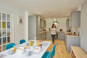 a woman in a kitchen with a table with food on it at Listers Nest in Exley