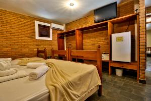 a bedroom with two beds and a tv on a brick wall at Hotel Fazenda Campo dos Sonhos in Socorro