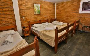 a room with three beds and a brick wall at Hotel Fazenda Campo dos Sonhos in Socorro