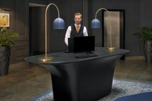 a man standing behind a desk with a computer at Mövenpick Hotel The Hague in The Hague