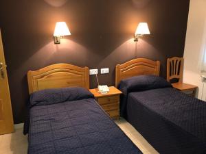 a bedroom with two beds and two lamps on the wall at Hotel Gil in Montanejos