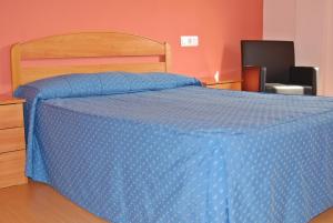 a bed with a blue comforter in a bedroom at Hotel Gil in Montanejos