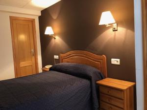 a bedroom with a blue bed and two lights on the wall at Hotel Gil in Montanejos