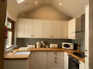 eine Küche mit weißen Schränken und einem Waschbecken in der Unterkunft Nab View Cottage in Whalley