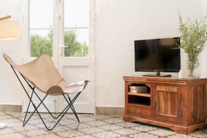 a chair in a living room with a television on a wooden cabinet at Finca Es Pi in Alaior