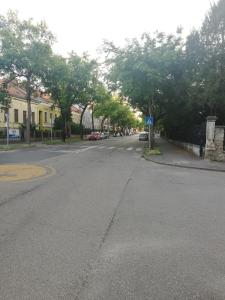 an empty street with trees and cars on the road at GOLD 2 Apartman in Sopron