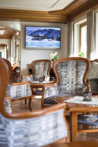 a room with chairs and tables and a flat screen tv at Hotel Waldheim Garni in Mayrhofen