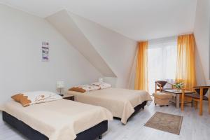 a bedroom with two beds and a table and a window at Perła Bałtyku in Pustkowo