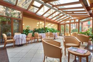 um restaurante com mesas e cadeiras num jardim de Inverno em Hotel Careni Villa Italia em Finale Ligure
