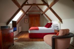 a bedroom with a bed and a chair in a attic at Whatley Manor in Malmesbury