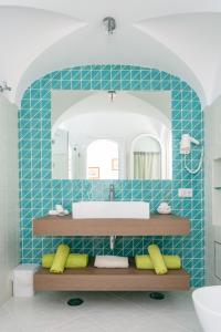 La salle de bains est pourvue de carrelage bleu, d'un lavabo et d'un miroir. dans l'établissement Aldarogi, à Capri