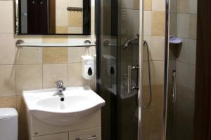 a bathroom with a sink and a glass shower stall at Hostel Rest in Kraków