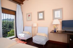 a bedroom with two blue chairs and a television at Hotel Rural Posada del Moro in Cazalla de la Sierra