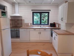 a kitchen with white cabinets and a sink and a window at Gîte avec SPA privé près zoo Beauval et châteaux in Oisly