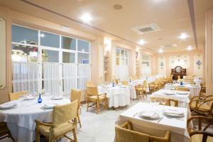 a restaurant with white tables and chairs and windows at Hotel Rural Posada del Moro in Cazalla de la Sierra
