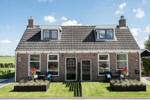een stenen huis met ramen en stoelen in de tuin bij Vakantiewoning Oer it fjild in Holwerd