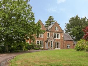 een oud bakstenen huis met een tuin ervoor bij The Old Vicarage in Tiverton