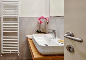 a bathroom with a white sink and pink flowers at Pegaso Civico2 in Garda