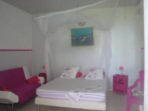 a bedroom with a canopy bed and a couch at ESCALE CREOLE in Terre-de-Haut