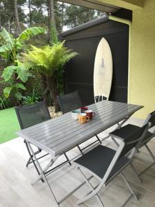 una mesa de picnic con sillas y una tabla de surf contra una pared en Villa patio terrasse privative océan 10 min a pied en Seignosse