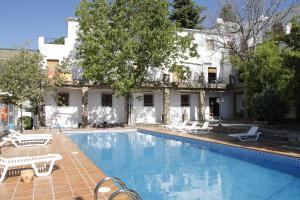 a swimming pool with white chairs and a building at Apartamentos Rurales Poqueira in Capileira