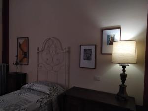 een slaapkamer met een bed met een lamp en foto's aan de muur bij Villa Carlotta in Sarzana
