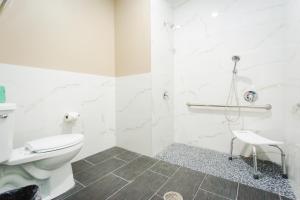 a white bathroom with a toilet and a shower at Budget Host Inn & Suites in Four Corners