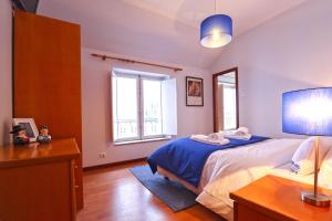 a bedroom with a bed with blue sheets and a mirror at Dolce Vianna - City Centre Rooms in Viana do Castelo