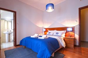 sypialnia z dużym łóżkiem i niebieskim kocem w obiekcie Dolce Vianna - City Centre Rooms w mieście Viana do Castelo