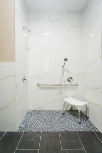 a bathroom with a shower and a stool at Budget Host Inn & Suites in Four Corners