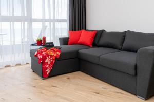 un sofá gris con almohadas rojas en la sala de estar en Aparthotel Primorsko en Primorsko