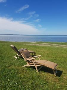 two lounge chairs sitting in the grass near the water at Kapitänshaus Meerblick in Langeneß +10 photos