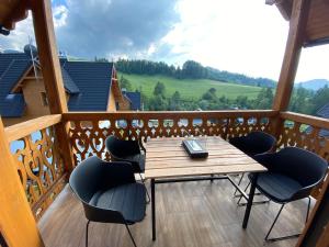 eine Holzterrasse mit einem Tisch und Stühlen auf dem Balkon in der Unterkunft Lajkonik in Jaworki