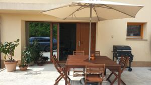 une table et des chaises en bois avec un parasol dans l'établissement Apartma Claudia, à Pivka